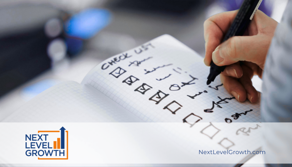 A hand holding a pen checks items off a handwritten checklist in a notebook, illustrating how elite leaders focus on doing less to multiply success. The Next Level Growth logo and website appear at the bottom of the image.