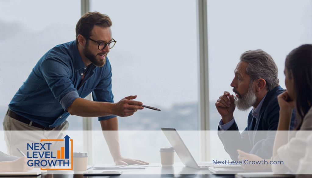 A man stands and gestures with a pen while speaking to two seated colleagues at a conference table, addressing business challenges. The Next Level Growth logo and website appear at the bottom.